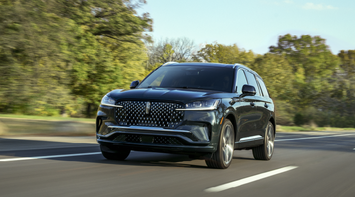 A 2025 Lincoln Black Label Aviator® SUV is being driven down a road lined with trees. | Magic City Lincoln in Roanoke VA