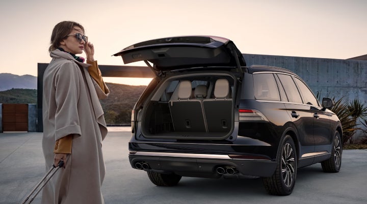 A woman approaches a 2026 Lincoln Aviator® SUV with its rear liftgate open. | Magic City Lincoln in Roanoke VA