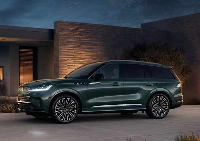A green 2027 Lincoln Aviator® SUV is parked outside a contemporary home. | Magic City Lincoln in Roanoke VA