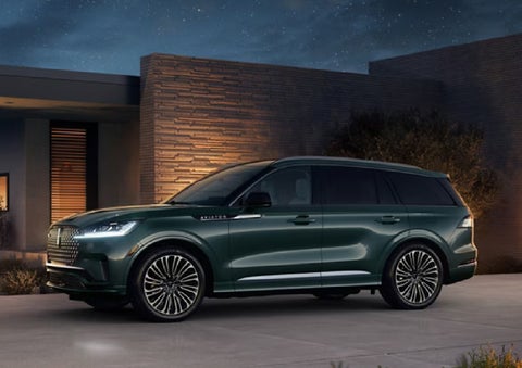 A green 2027 Lincoln Aviator® SUV is parked outside a contemporary home. | Magic City Lincoln in Roanoke VA