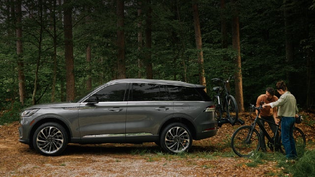 A father and son load e-bikes on a bike rack attached to a 2027 Lincoln Aviator® SUV. | Magic City Lincoln in Roanoke VA