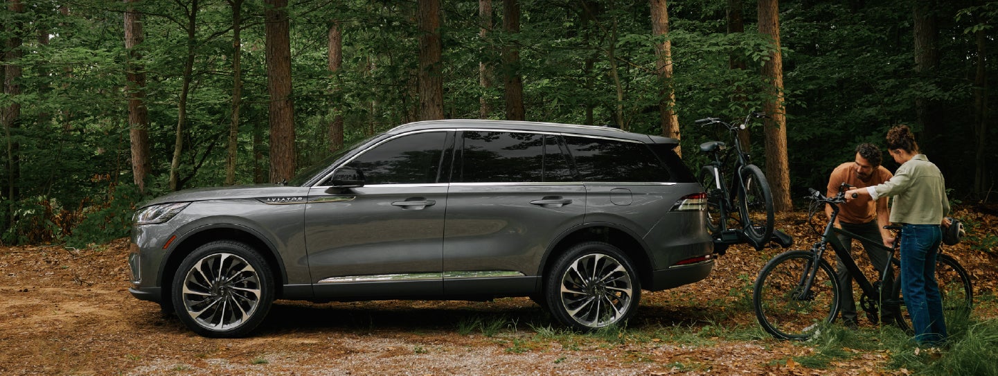 A father and son load e-bikes on a bike rack attached to a 2027 Lincoln Aviator® SUV. | Magic City Lincoln in Roanoke VA